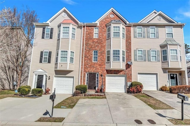 multi unit property with a garage, driveway, and brick siding