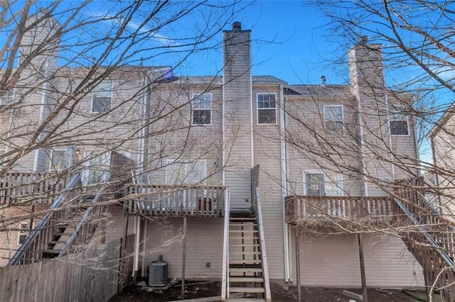 back of property featuring central AC, stairway, a chimney, and a balcony