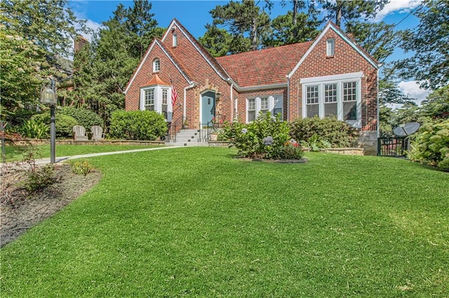 tudor house featuring brick siding and a front lawn