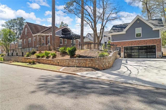 view of side of home with driveway, an attached garage, fence, and brick siding