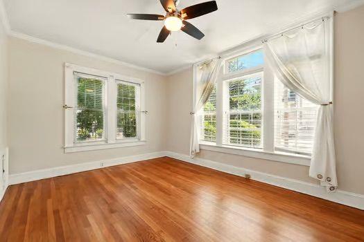 242 12th St NE Unit 1A, Atlanta, GA 30309 - spare room featuring healthy amount of natural light, crown molding, baseboards, and wood finished floors