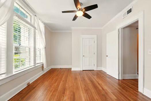 242 12th St NE Unit 1A, Atlanta, GA 30309 - unfurnished room featuring healthy amount of natural light, wood finished floors, ceiling fan, ornamental molding, and baseboards