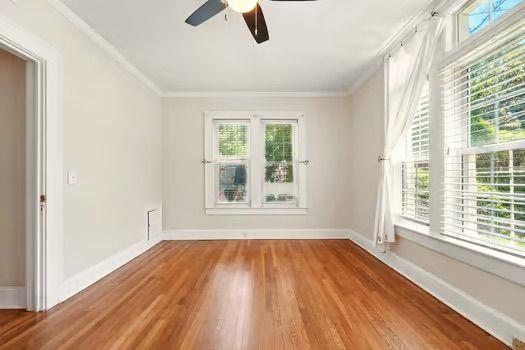 242 12th St NE Unit 1A, Atlanta, GA 30309 - spare room featuring wood finished floors, a ceiling fan, ornamental molding, and baseboards