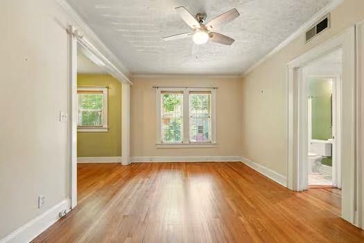 242 12th St NE Unit 1A, Atlanta, GA 30309 - unfurnished room featuring a ceiling fan, light wood-style floors, ornamental molding, and baseboards