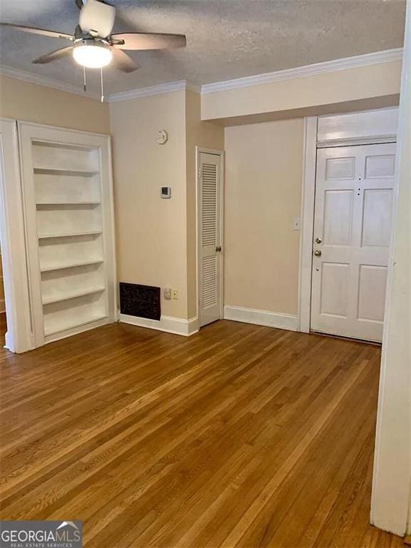 unfurnished living room with wood finished floors, crown molding, ceiling fan, baseboards, and a textured ceiling