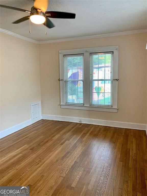 empty room with wood finished floors, baseboards, ornamental molding, and ceiling fan