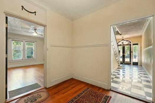 242 12th St NE Unit 1A, Atlanta, GA 30309 - hall with ornamental molding, healthy amount of natural light, wood finished floors, a chandelier, and baseboards