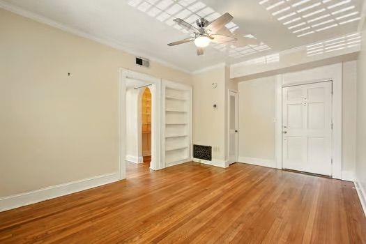 242 12th St NE Unit 1A, Atlanta, GA 30309 - unfurnished living room with ornamental molding, baseboards, wood finished floors, ceiling fan, and built in features