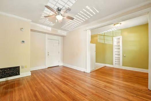 242 12th St NE Unit 1A, Atlanta, GA 30309 - unfurnished living room with ceiling fan, wood finished floors, crown molding, and baseboards
