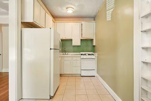 242 12th St NE Unit 1A, Atlanta, GA 30309 - kitchen with white appliances, built in features, a sink, light countertops, and baseboards