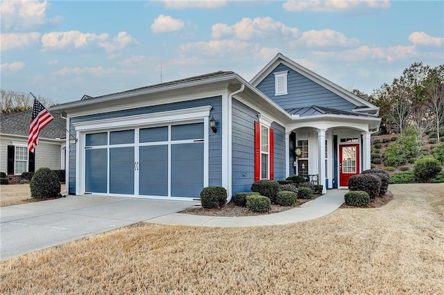 view of front of property with metal roof, a garage, concrete driveway, a standing seam roof, and a front yard