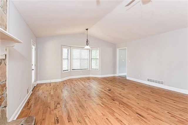 unfurnished dining area featuring lofted ceiling, ceiling fan, light wood-type flooring, and a fireplace