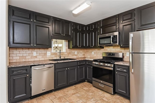 kitchen featuring decorative backsplash, appliances with stainless steel finishes, light stone counters, and sink