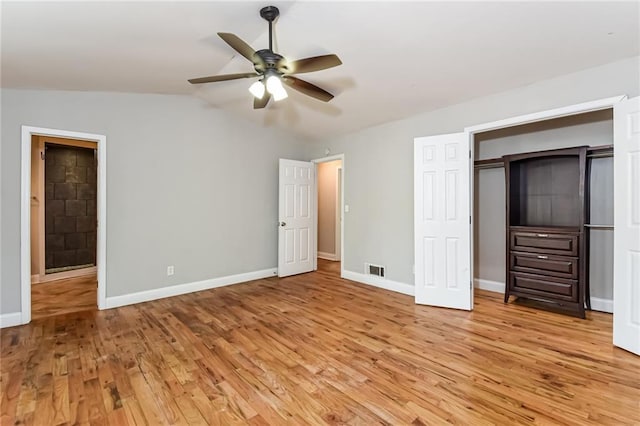 unfurnished bedroom featuring light wood-type flooring, a closet, vaulted ceiling, and ceiling fan