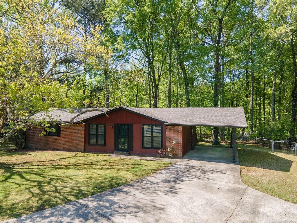 ranch-style home featuring concrete driveway, an attached carport, a front lawn, and brick siding
