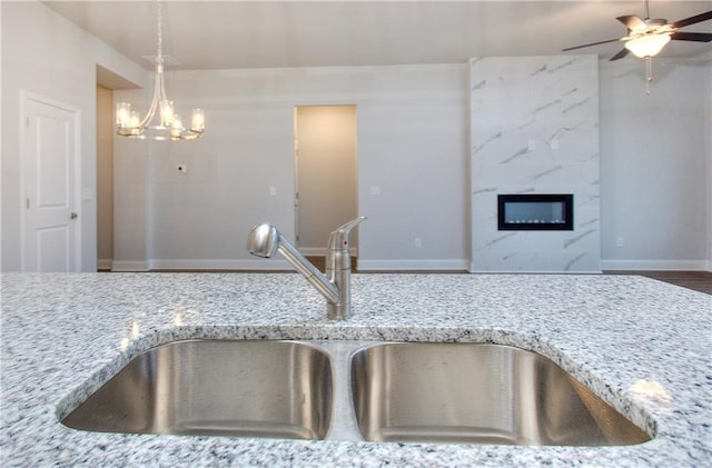 96 Sherwood Dr, Commerce, GA 30529 - room details with a high end fireplace, ceiling fan with notable chandelier, light stone counters, and a sink