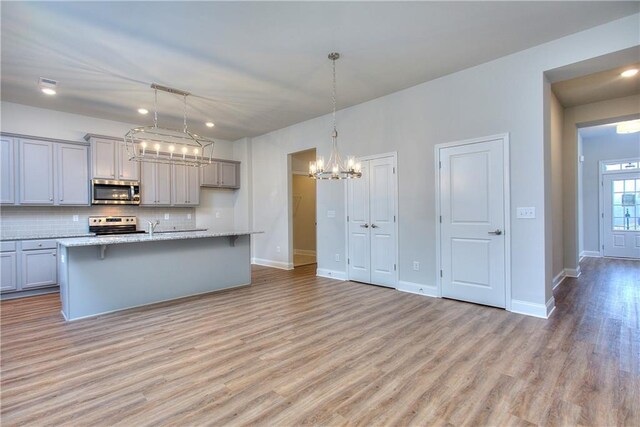96 Sherwood Dr, Commerce, GA 30529 - kitchen featuring stainless steel appliances, light wood-type flooring, a notable chandelier, decorative backsplash, and gray cabinetry