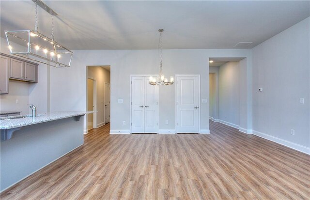 96 Sherwood Dr, Commerce, GA 30529 - unfurnished living room with light wood finished floors, baseboards, a sink, and a notable chandelier