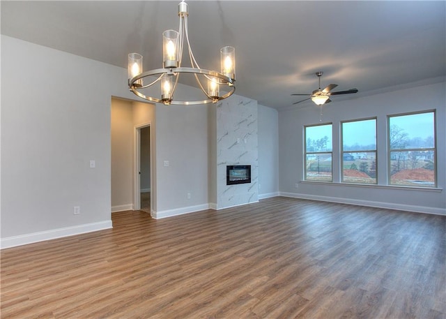 96 Sherwood Dr, Commerce, GA 30529 - unfurnished living room featuring ceiling fan with notable chandelier, baseboards, and wood finished floors