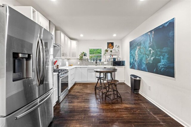 3143 Church St, East Point, GA 30344 - kitchen featuring appliances with stainless steel finishes, wall chimney range hood, dark wood-style flooring, backsplash, and recessed lighting