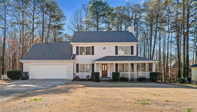 colonial house with driveway, a chimney, an attached garage, a front lawn, and a porch