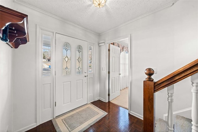 foyer entrance featuring a textured ceiling, baseboards, stairs, and crown molding