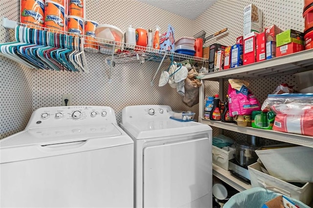 clothes washing area with washing machine and dryer, laundry area, a textured ceiling, and wallpapered walls