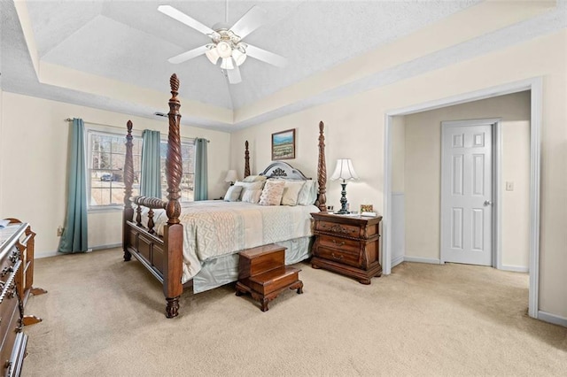 bedroom featuring baseboards, a tray ceiling, a ceiling fan, and light colored carpet