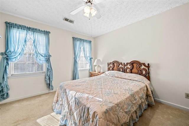 carpeted bedroom featuring a textured ceiling, ceiling fan, visible vents, and baseboards