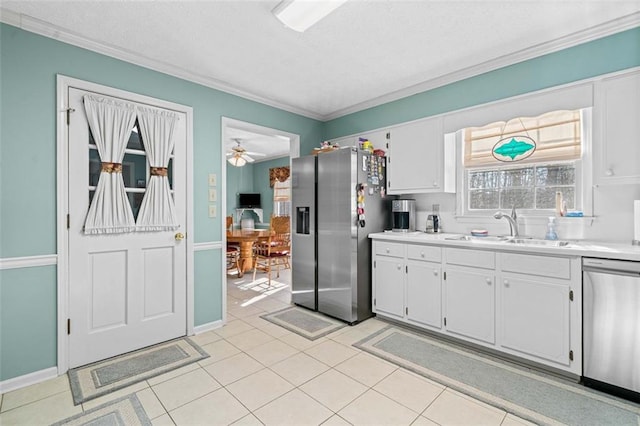 kitchen featuring a sink, white cabinetry, light countertops, ornamental molding, and appliances with stainless steel finishes