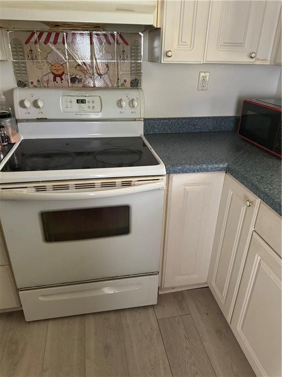 kitchen featuring white cabinetry, light hardwood / wood-style floors, and white range with electric cooktop