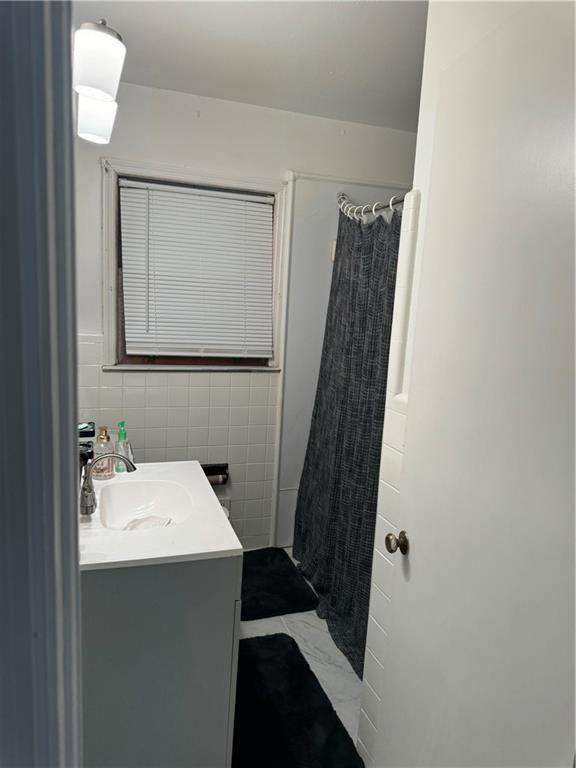 bathroom with vanity, a shower with shower curtain, and tile walls