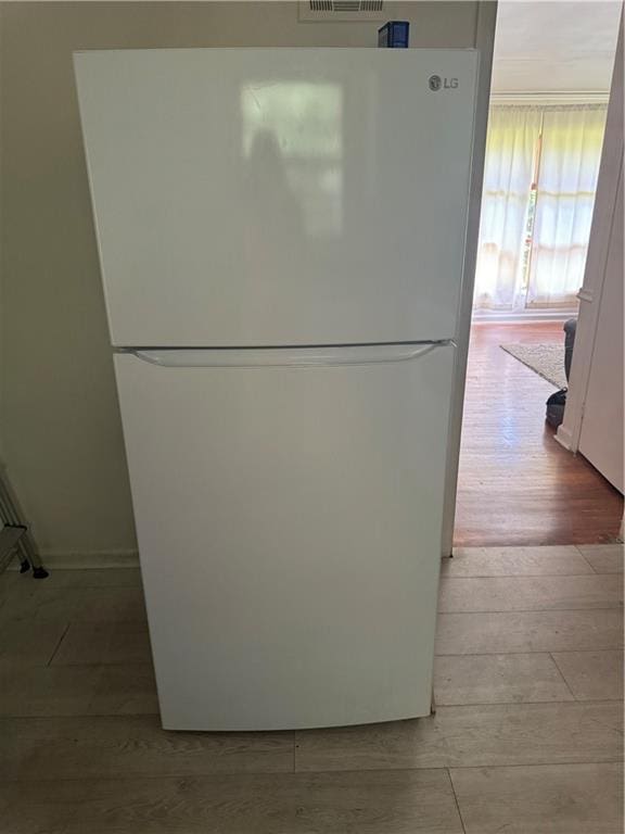 room details featuring light hardwood / wood-style floors and white fridge