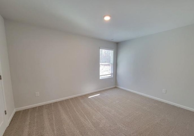 empty room featuring light colored carpet and baseboards