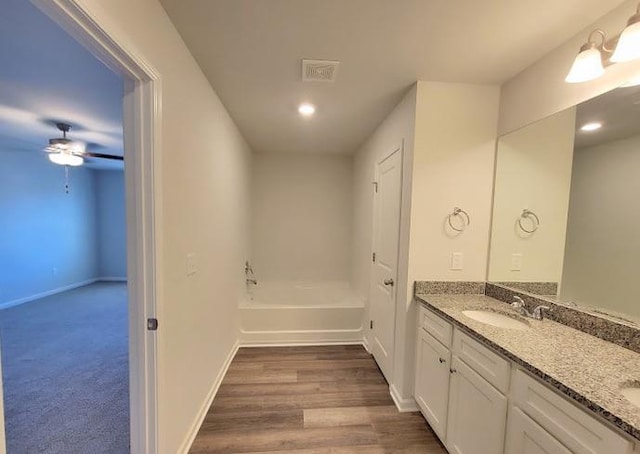 bathroom featuring double vanity, ceiling fan, recessed lighting, a tub to relax in, and baseboards
