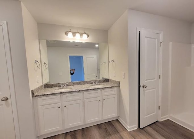 bathroom featuring wood finished floors, double vanity, and baseboards