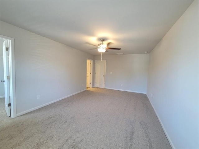 carpeted empty room with ceiling fan and baseboards
