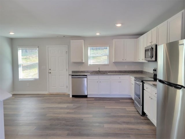 kitchen featuring appliances with stainless steel finishes, a sink, healthy amount of natural light, white cabinetry, and recessed lighting
