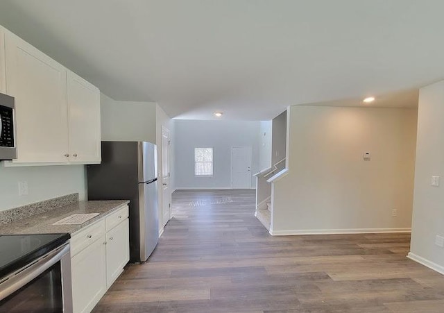 kitchen featuring appliances with stainless steel finishes, white cabinetry, recessed lighting, baseboards, and light wood-style flooring