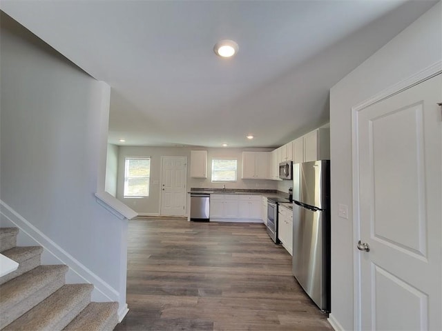 kitchen with stainless steel appliances, a sink, recessed lighting, white cabinetry, and dark wood-style flooring