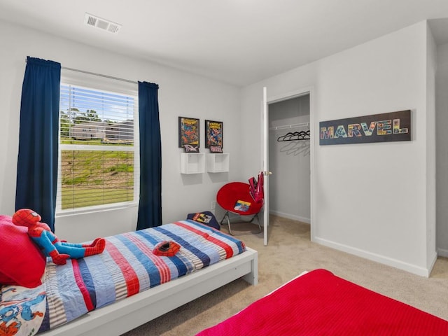 bedroom with a walk in closet, a closet, and carpet flooring