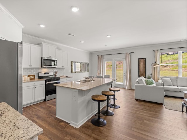 kitchen with white cabinetry, appliances with stainless steel finishes, a kitchen island with sink, and sink