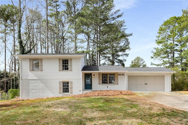 split level home featuring a garage, a front yard, concrete driveway, and brick siding