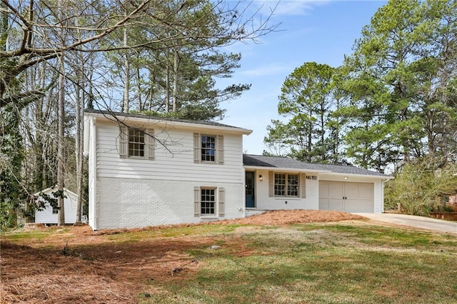 tri-level home with a garage, a front yard, brick siding, and driveway