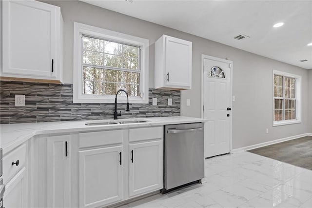 kitchen with tasteful backsplash, dishwasher, sink, white cabinets, and light stone countertops