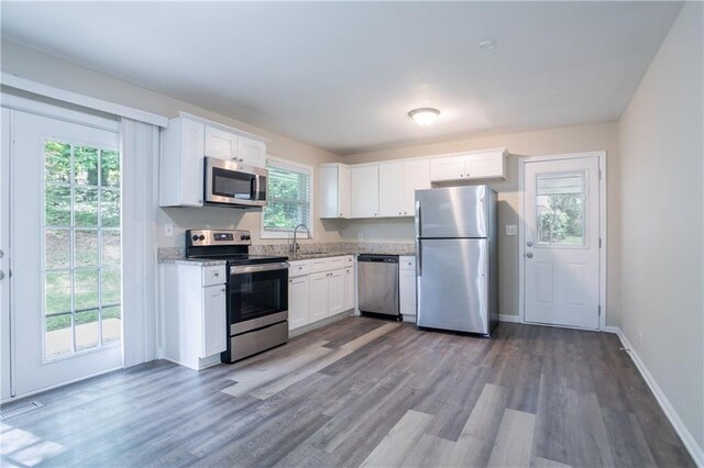 5795 Deerfield Trl, Atlanta, GA 30349 - kitchen with appliances with stainless steel finishes, a sink, wood finished floors, and white cabinets