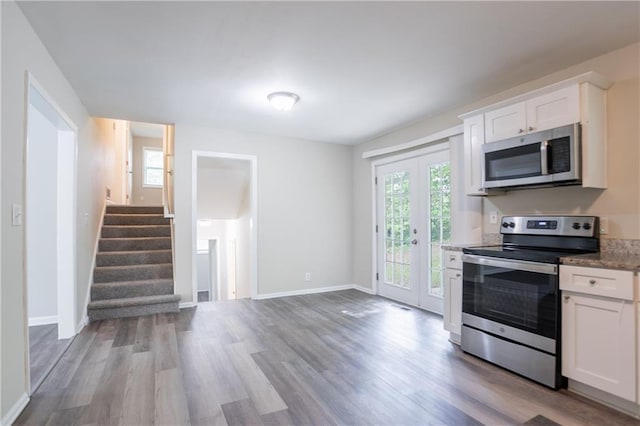 5795 Deerfield Trl, Atlanta, GA 30349 - kitchen featuring stainless steel appliances, wood finished floors, white cabinets, and baseboards