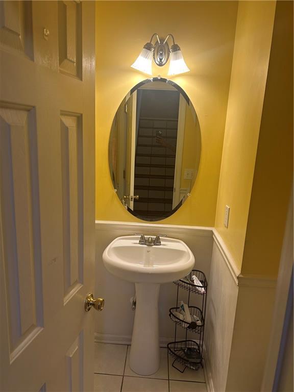 bathroom with a wainscoted wall, a sink, and tile patterned flooring