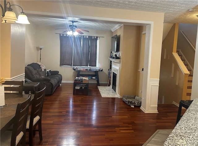 living room with a textured ceiling, a fireplace, wood finished floors, a ceiling fan, and stairs