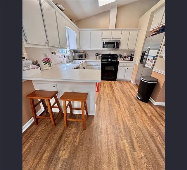 5624 Ryan Way, Flowery Branch, GA 30542 - kitchen featuring appliances with stainless steel finishes, a peninsula, light wood-type flooring, lofted ceiling, and light countertops